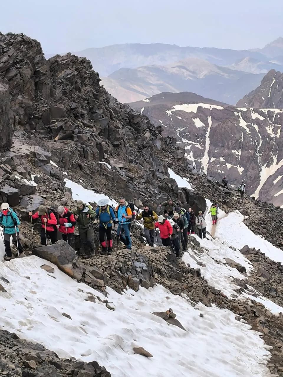 Un groupe de randonneurs sur une pente rocheuse parsemée de neige